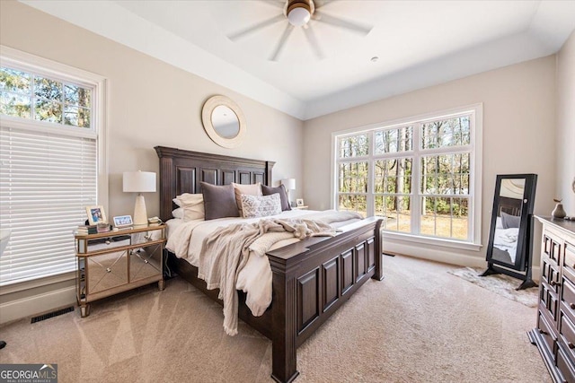 bedroom with visible vents, light colored carpet, and ceiling fan