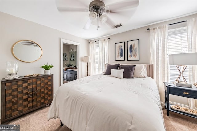 bedroom featuring visible vents, carpet, ensuite bathroom, and a ceiling fan