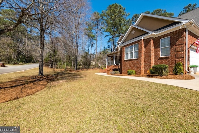 view of side of home featuring a garage, concrete driveway, a yard, and brick siding