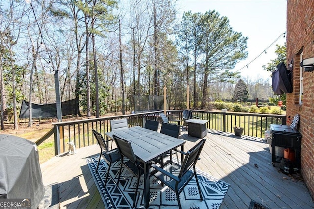 wooden deck featuring a trampoline, a grill, and outdoor dining space