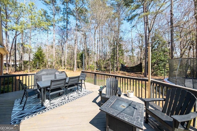 wooden deck with outdoor dining space and a trampoline