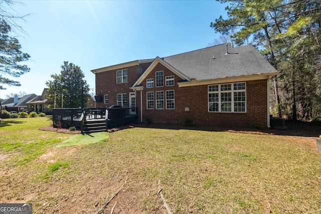 back of property featuring brick siding, a lawn, and a deck