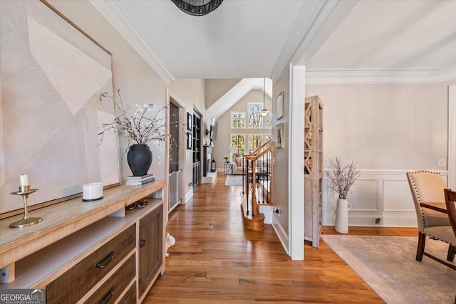 entrance foyer featuring a decorative wall, wainscoting, crown molding, and wood finished floors