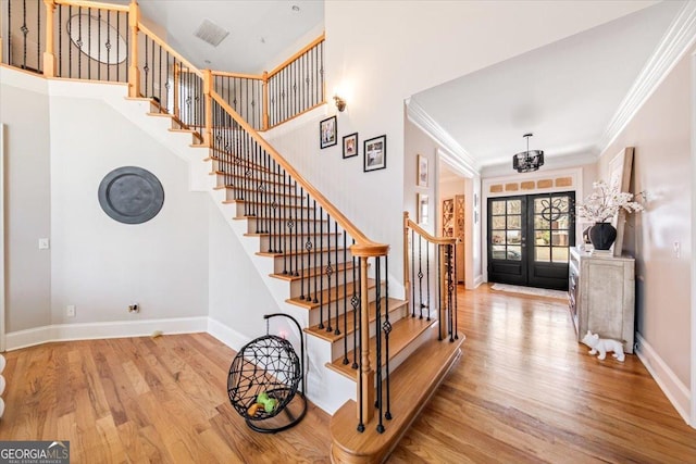 foyer entrance with visible vents, ornamental molding, wood finished floors, french doors, and baseboards