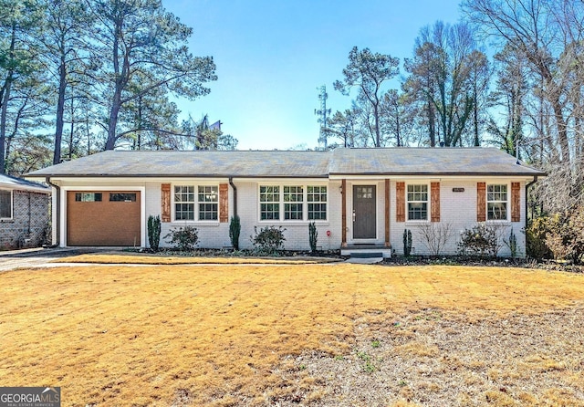 single story home with brick siding, an attached garage, driveway, and a front lawn