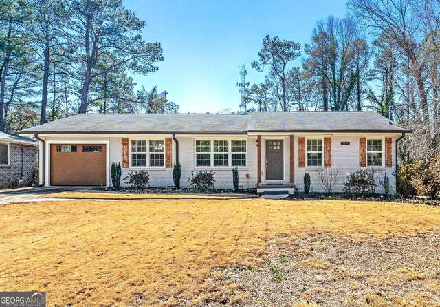 single story home with a front yard, an attached garage, brick siding, and driveway
