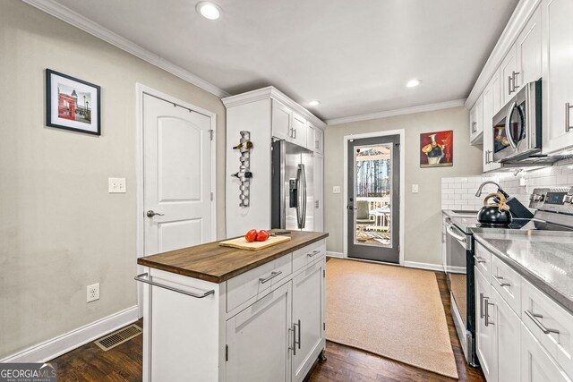 kitchen featuring visible vents, butcher block countertops, ornamental molding, tasteful backsplash, and appliances with stainless steel finishes