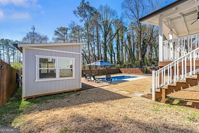 view of yard featuring stairs, an outbuilding, a fenced backyard, and a fenced in pool