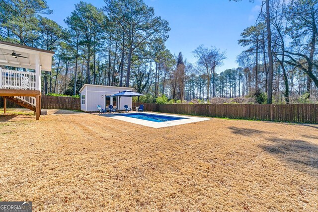 view of yard with an outbuilding, a ceiling fan, a patio, a fenced backyard, and a fenced in pool