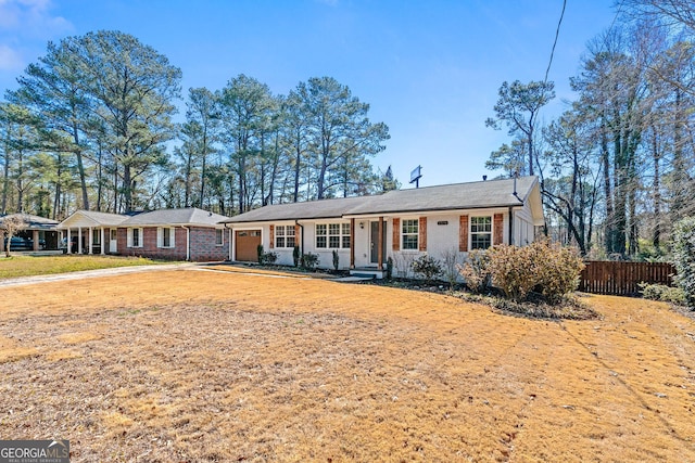 ranch-style home with a garage, brick siding, and fence