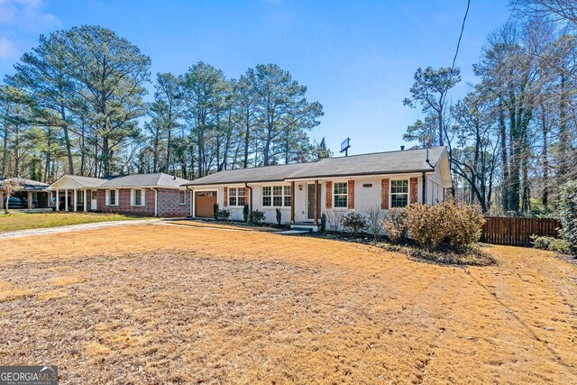 ranch-style home with a garage, brick siding, and fence