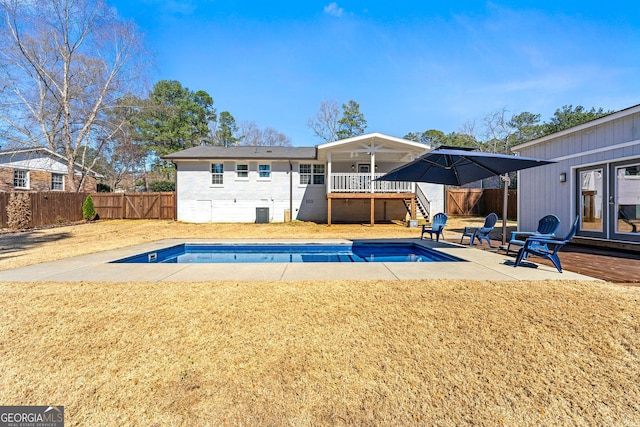 back of house featuring a deck, a lawn, a fenced backyard, and a fenced in pool