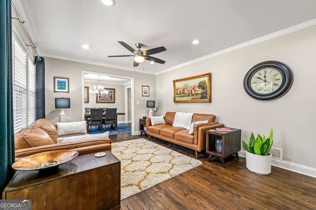 living area featuring wood finished floors, visible vents, baseboards, ornamental molding, and ceiling fan with notable chandelier