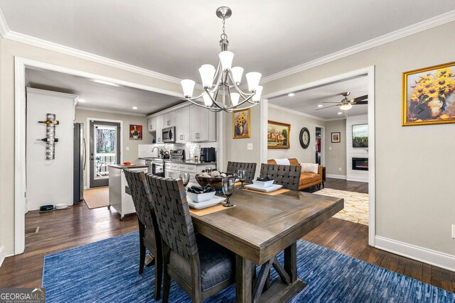 dining room with dark wood-style floors, a glass covered fireplace, baseboards, and ornamental molding