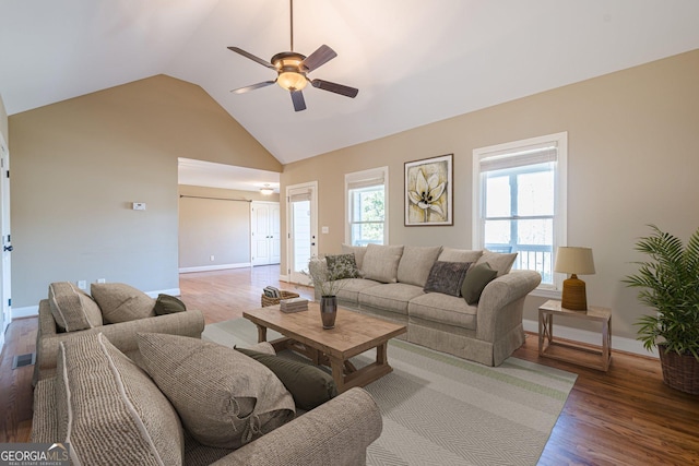 living area featuring visible vents, high vaulted ceiling, a ceiling fan, wood finished floors, and baseboards