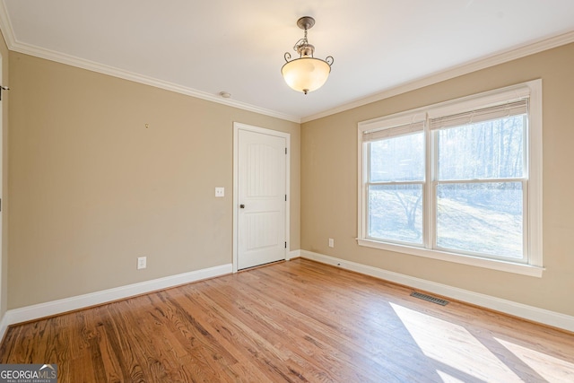 empty room featuring visible vents, baseboards, light wood-style floors, and ornamental molding