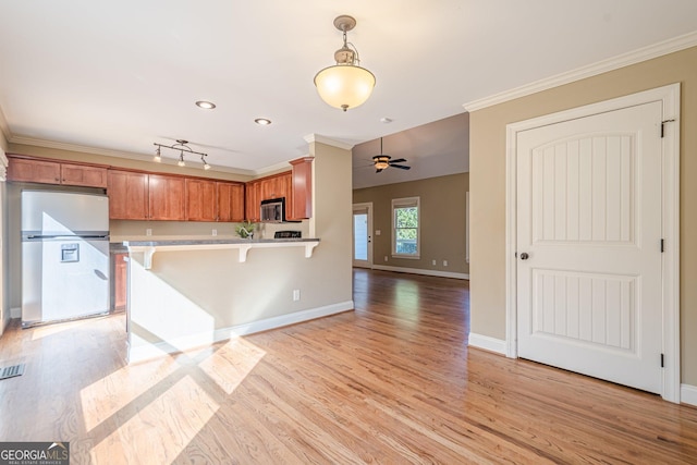 kitchen with a breakfast bar, light wood-style flooring, ornamental molding, stainless steel appliances, and decorative light fixtures