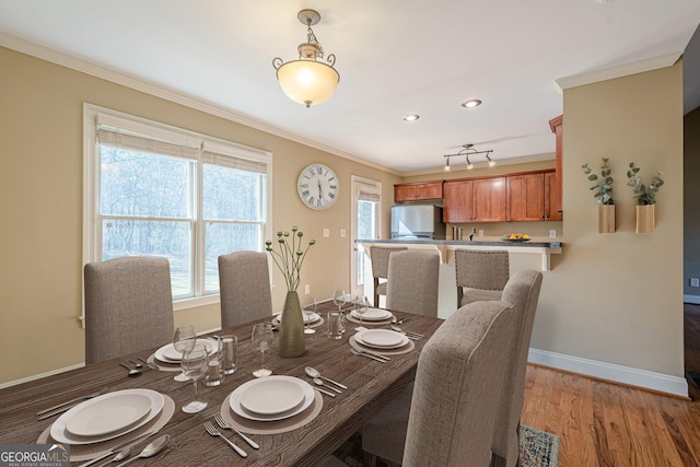 dining space featuring crown molding, baseboards, and light wood-type flooring