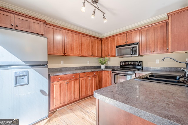 kitchen with brown cabinetry, light wood-style flooring, appliances with stainless steel finishes, and a sink