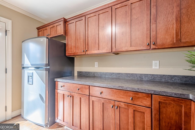 kitchen featuring brown cabinetry, freestanding refrigerator, and ornamental molding