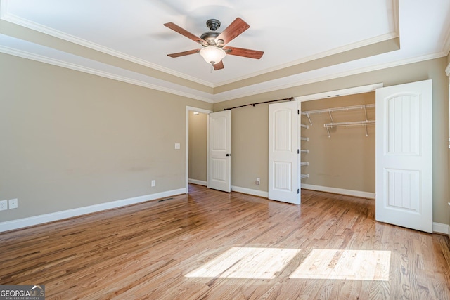 unfurnished bedroom with crown molding, light wood-style floors, baseboards, and a closet