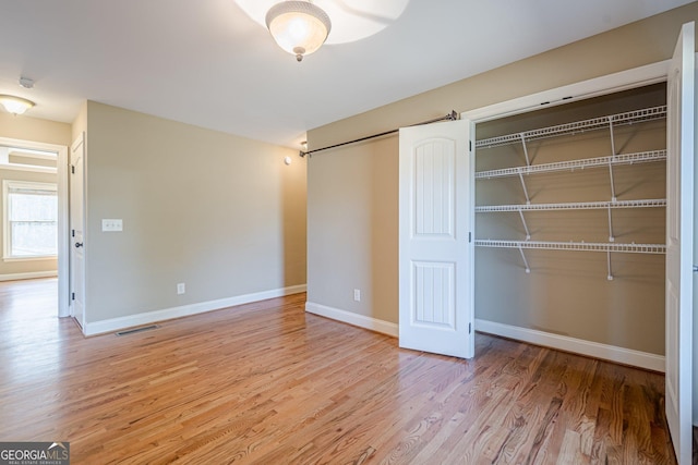 unfurnished bedroom featuring visible vents, baseboards, and wood finished floors