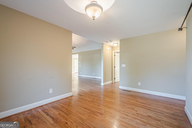 unfurnished room with light wood-style flooring, visible vents, and baseboards