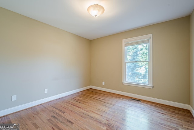 unfurnished room with visible vents, baseboards, and wood finished floors