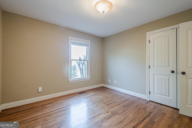 unfurnished room with visible vents, baseboards, and wood finished floors