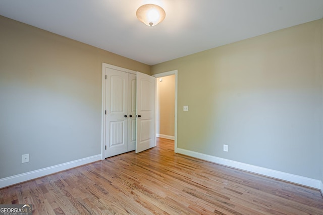 unfurnished bedroom featuring baseboards, light wood-type flooring, and a closet