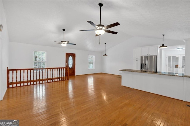 unfurnished living room featuring lofted ceiling, a textured ceiling, ceiling fan, and light wood finished floors