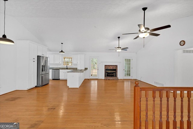 unfurnished living room with visible vents, a fireplace, a textured ceiling, and light wood-style floors