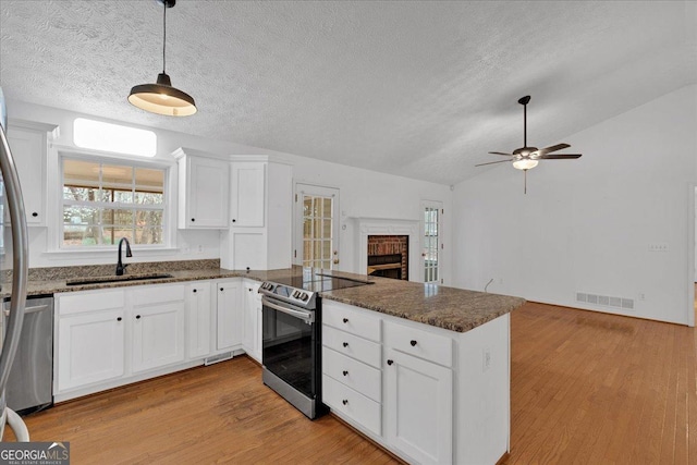 kitchen with visible vents, a sink, appliances with stainless steel finishes, a peninsula, and lofted ceiling