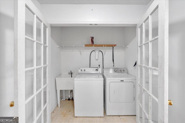 laundry area featuring laundry area, light floors, separate washer and dryer, and a sink