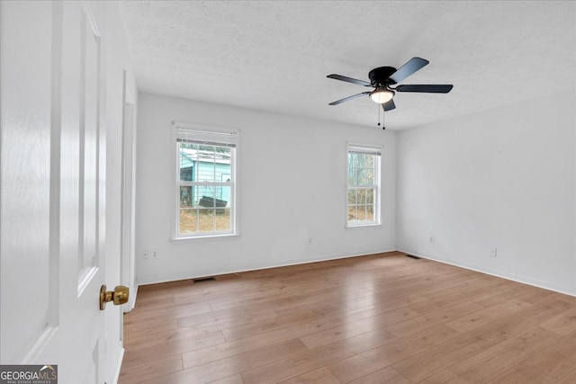 empty room featuring visible vents, a textured ceiling, light wood-style flooring, and a ceiling fan