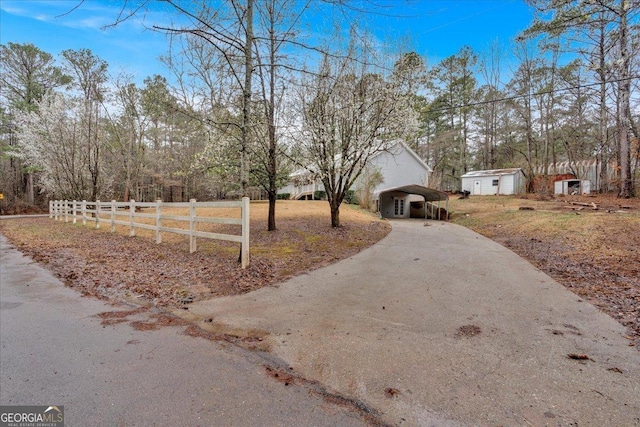 exterior space with a detached carport, driveway, and fence