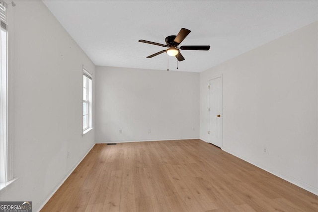 unfurnished room with light wood-style flooring, a ceiling fan, and baseboards