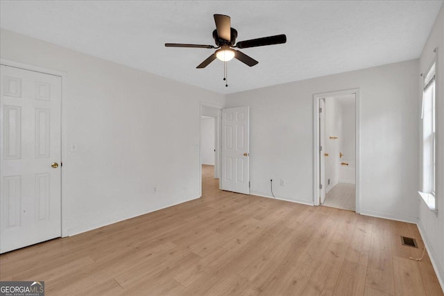 unfurnished bedroom with baseboards, light wood-style flooring, and ensuite bathroom