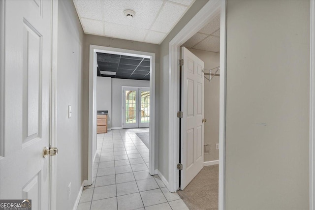 hall with light tile patterned floors, french doors, baseboards, and a drop ceiling