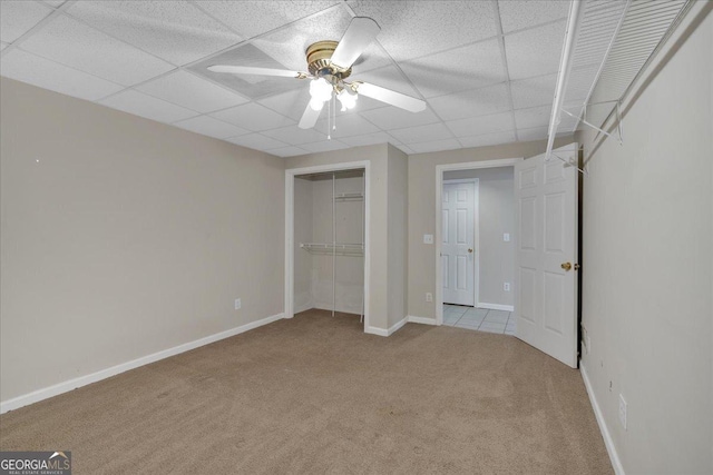 unfurnished bedroom featuring carpet, a paneled ceiling, baseboards, and a ceiling fan