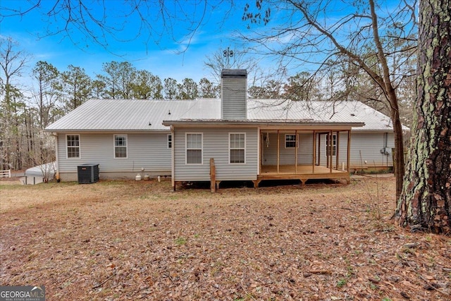 rear view of property featuring central air condition unit, metal roof, and a chimney