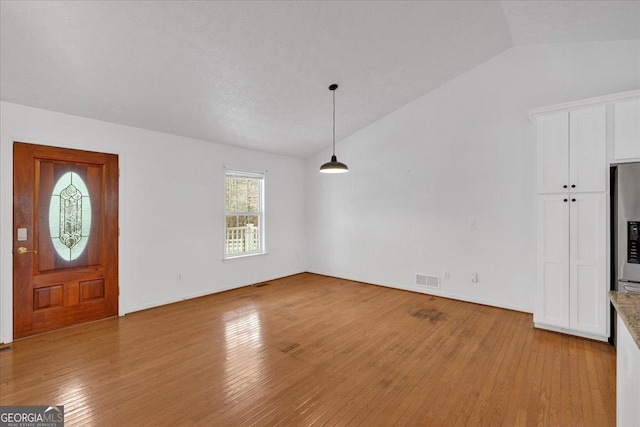 entryway with vaulted ceiling, visible vents, and light wood-type flooring