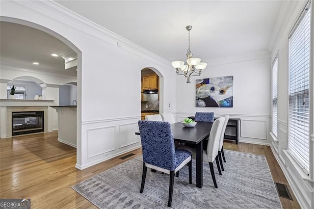 dining space with a chandelier, visible vents, crown molding, and wood finished floors