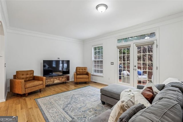 living room with baseboards, crown molding, light wood-style flooring, and french doors