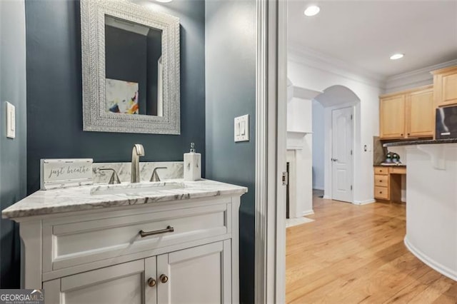 bathroom featuring baseboards, ornamental molding, recessed lighting, wood finished floors, and vanity