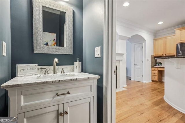 bathroom with vanity, crown molding, recessed lighting, baseboards, and wood finished floors