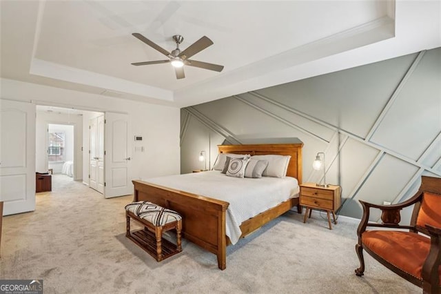 bedroom featuring a tray ceiling, light carpet, and a ceiling fan