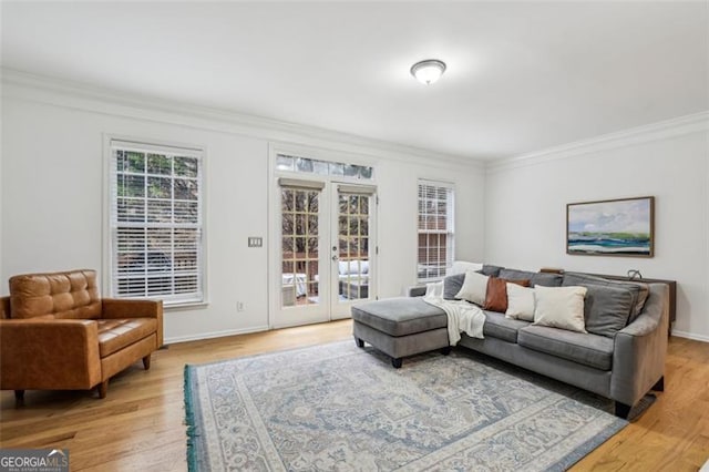 living room with crown molding, light wood-style flooring, french doors, and baseboards