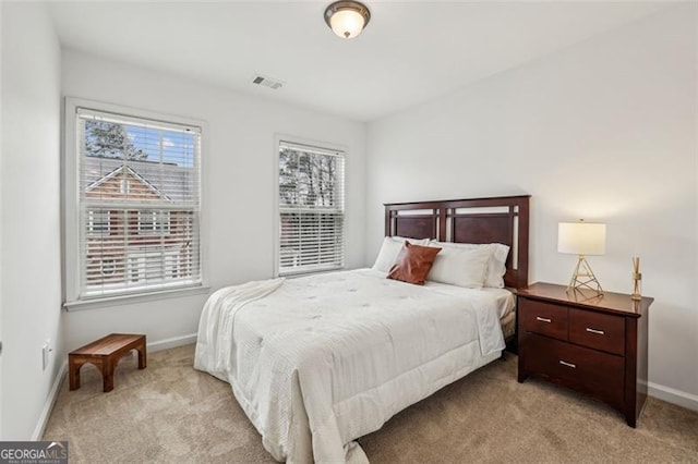 bedroom with baseboards, visible vents, and light carpet