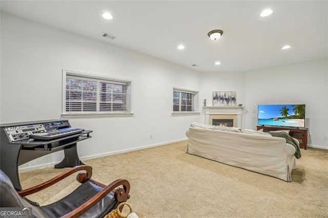 living room featuring recessed lighting, carpet, visible vents, and a lit fireplace